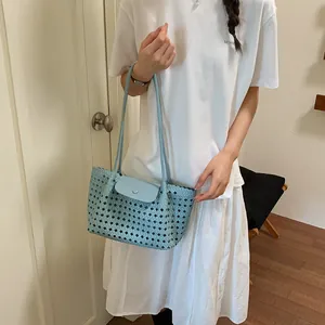 Modische hellblaue geflochtene Tragetasche von einem Model im Sommeroutfit