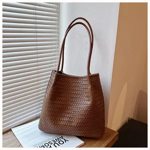 Stylish large brown vintage woven tote bag displayed on a wooden table with soft lighting