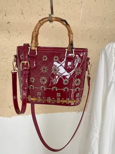 Wine red patent leather quilted handbag with bamboo handle and gold floral studs