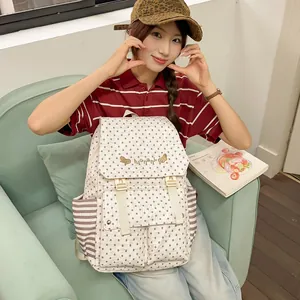 Detailed shot of fashionable cream star pattern backpack worn by model on green sofa.
