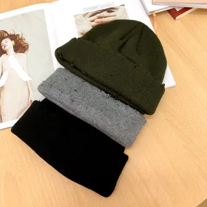 Vue détaillée de trois bonnets en maille déchirée en vert olive, gris et noir.