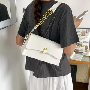 Lifestyle view of a chic white crossbody bag with gold chain strap and buckle detail