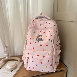 Dettaglio di uno zaino scolastico rosa a pois con ricamo di un gatto carino.