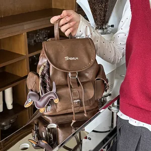 Vintage brown PU leather backpack featuring a cute dachshund charm in a cozy cafe