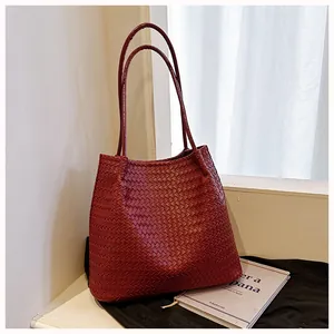 Detail view of a vintage burgundy woven tote bag in a lifestyle indoor setting.