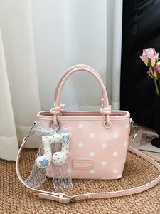 Chic pink polka dot handbag with a musical note charm and elegant white lace detail strap