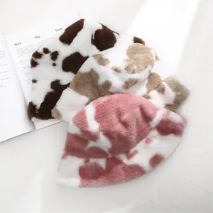 Detailed macro view of plush cow print bucket hats in various colors for winter.
