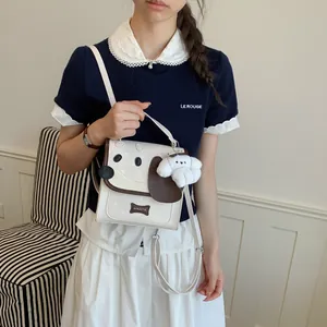 Cute dog-themed small crossbody bag with plush charm shown in a lifestyle model shot.