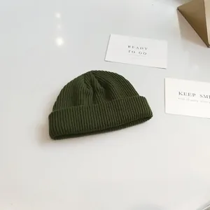 Close-up of dark green knitted docker cap showing its vertical rib texture detail.