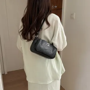 Sac à bandoulière noir texturé minimaliste porté avec une chemise en lin vert clair de dos.