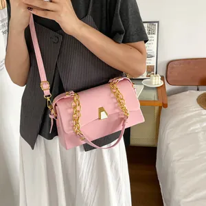 Model carrying a pink square shoulder bag with gold chain detail in a lifestyle setting