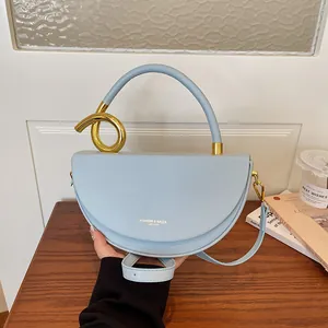 Nahaufnahme einer hellblauen Satteltasche aus Leder mit einzigartigem Goldknoten-Griffdetail