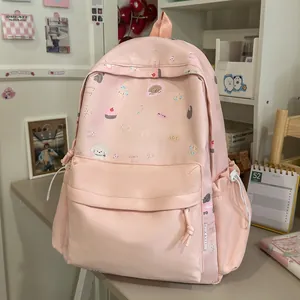 Cute pink student backpack featuring sweet cartoon illustrations in a cozy study room setting