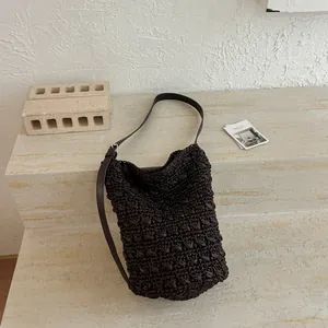 Minimalistische dunkelbraune Stroh-Eimertasche mit verstellbarem Lederriemen für den Urlaub.