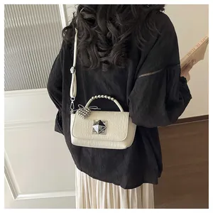 Detailed back view of a chic cream textured mini crossbody bag featuring a unique beaded handle