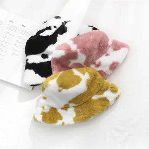 A selection of three colorful cow print plush bucket hats designed for winter warmth
