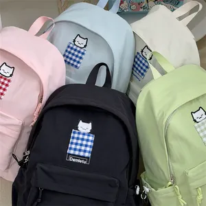 Detailed view of colorful dopamine-style backpacks with cute cat embroidery and checkered pockets.