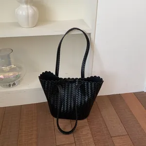 Close-up detail showing the intricate woven texture and scalloped top of this black bucket bag.