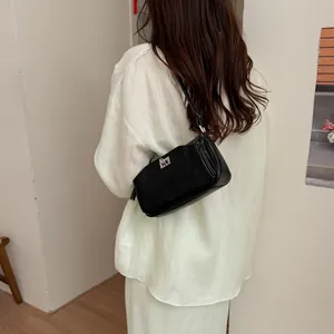 Sac à bandoulière baguette noir minimaliste pour femme avec une tenue en lin chic.