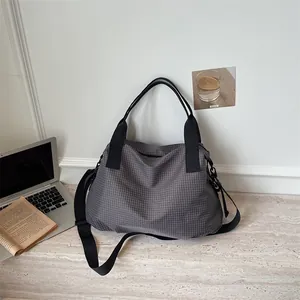 Grande borsa da viaggio a scacchi grigi per sport e fitness, appoggiata su un tavolo chiaro.