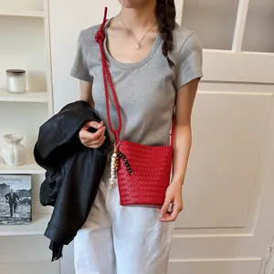 Rote gewebte Eimertasche mit Perlenriemen an einem Model für einen lässigen Look