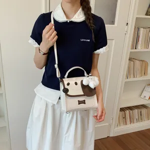 Detailed view of a cute dog-themed white crossbody bag featuring a plush puppy keychain