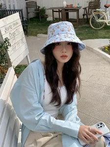 Gros plan d'une femme portant un bob à fleurs bleu clair dans un café en plein air