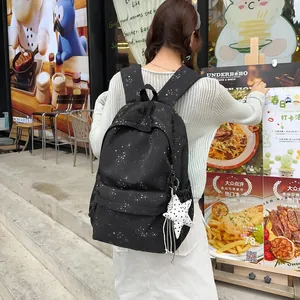 Rucksack mit schwarzem Sternenmuster, präsentiert von einem Model im Freien.