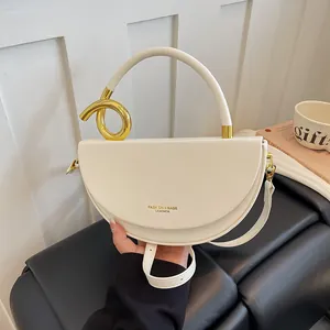 Detailansicht der cremefarbenen Satteltasche mit goldenem Metallgriff