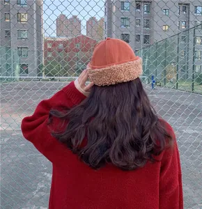 Back view of woman wearing a warm orange plush docker hat in an outdoor setting