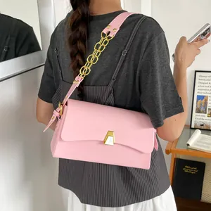 Chic pink square shoulder bag with elegant gold chain strap worn by model in a lifestyle setting