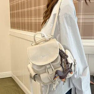 Stylish cream leather backpack with decorative chocolate dachshund charm and logo detail