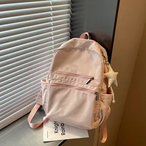 Vista detallada de una mini mochila rosa ligera con un llavero de estrella