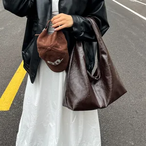 Vista detallada de un gran bolso hobo marrón vintage llevado por una modelo urbana.