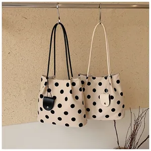 Detailed view of retro polka dot tote bags in cream and black hanging from a rod