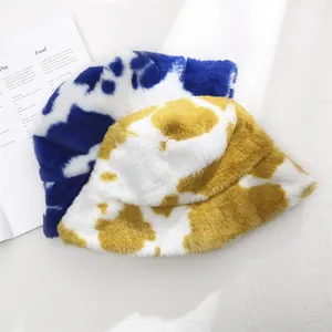 Detail view of plush cow print bucket hats in blue and yellow for winter style