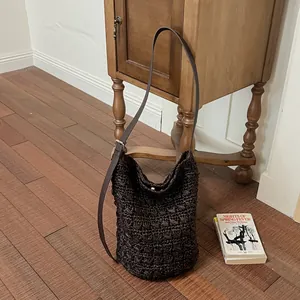 Detailaufnahme einer dunkelbraunen Stroh-Eimertasche mit verstellbarem Lederriemen