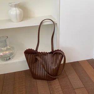 Close-up detail of a large brown woven bucket bag featuring elegant scalloped edges for summer.