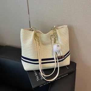 Stylish cream woven tote bag with navy stripes and a cute monster charm