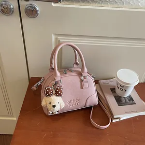 Elegant pink pebble leather Boston handbag with a cute plush puppy charm for commuting