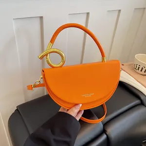 Detailansicht einer leuchtend orangefarbenen Satteltasche mit einzigartigem Goldgriff.