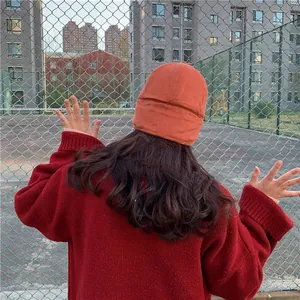 Back view of a woman wearing an orange plush earflap hat for winter warmth and style.