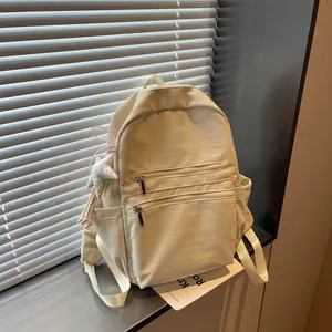 Mochila minimalista de nailon crema con cremalleras frontales y colgante de estrella