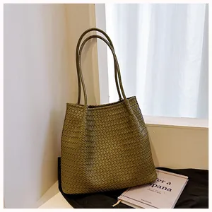 Macro view showing the detailed texture of an olive green retro woven tote bag for women
