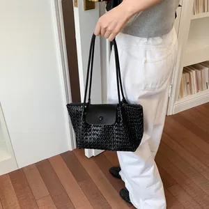 Lifestyle-Detail einer schwarzen gewebten Tragetasche mit minimalistischer Lederklappe.