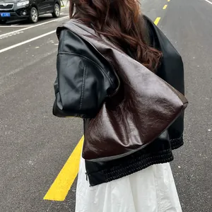 Bolso hobo grande vintage marrón de cuero suave plisado mostrado por una modelo en la calle