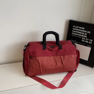 Detailed close-up view of red travel duffel bag with grid pattern and black handle