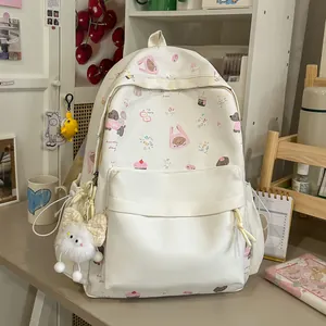 Close-up detail of white cute backpack featuring cartoon animal patterns and a plush keychain