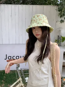 Vue détaillée d'un bob à fleurs vert clair pour femme avec sangle coupe-vent réglable