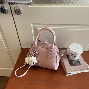 Pink textured leather Boston handbag with cute puppy charm on a wooden desk